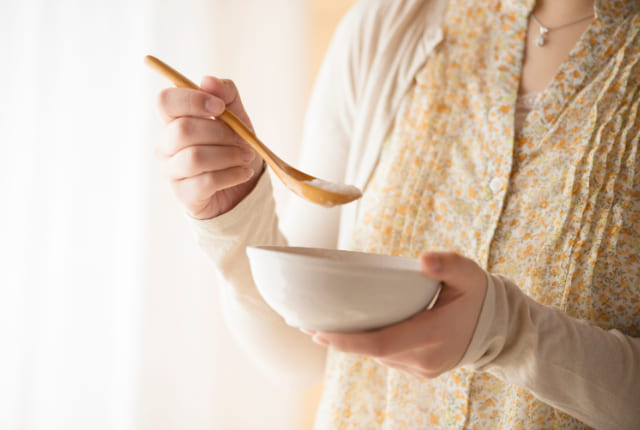 おかゆを持つ女性の手元